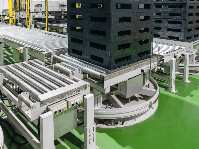 Industrial conveyor system transporting large black pallets